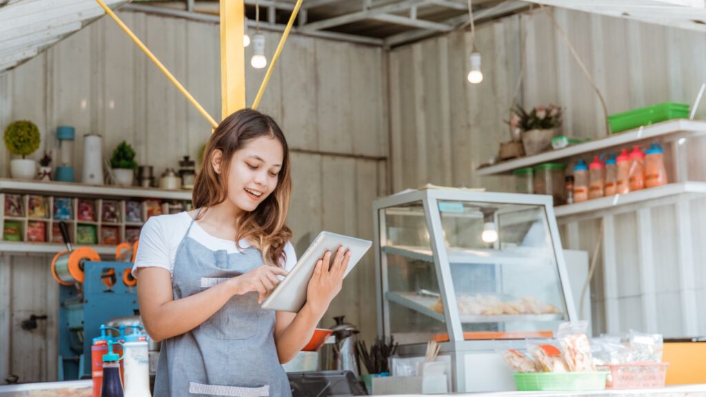 A food vendor using a tablet to update social media posts, showing the integration of social media management tools in small business operations.